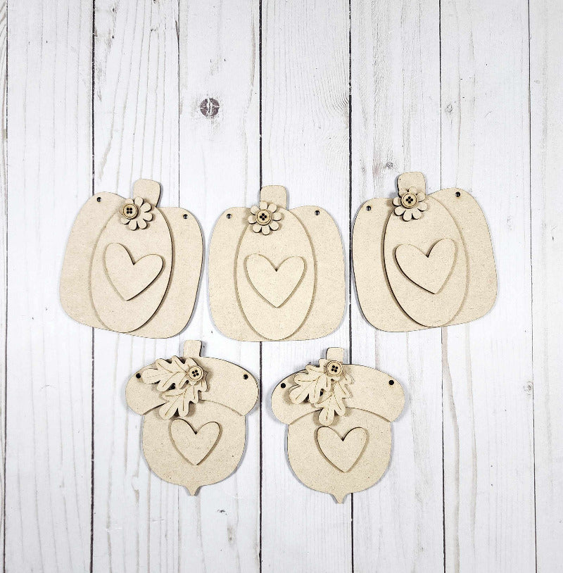 Set of decorative pumpkin cutouts with heart-shaped tags and floral elements on a wooden background