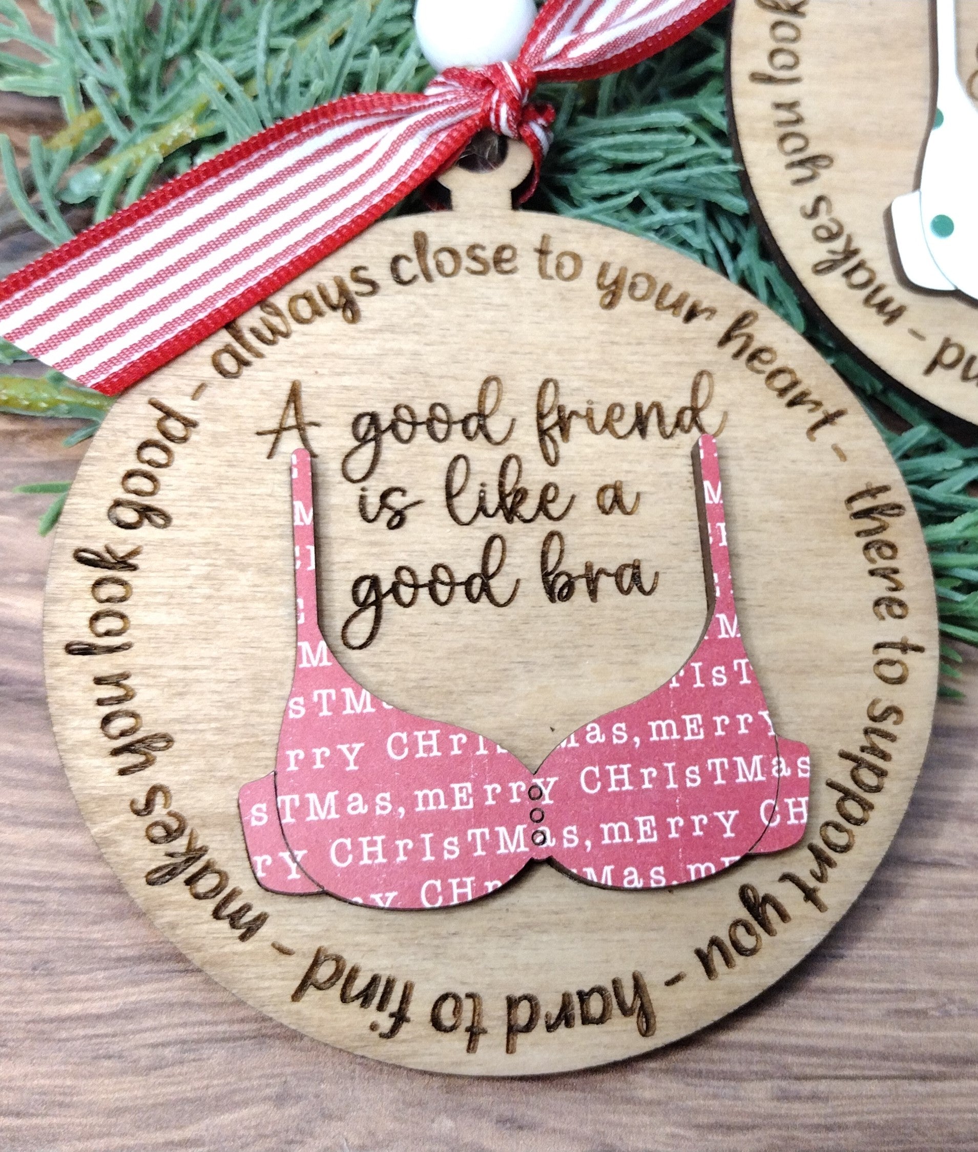Wooden ornament with polka dot bra design and humorous text on a wooden surface.