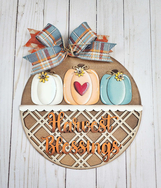 Decorative sign with pumpkins and 'Harvest Blessings' text on a wooden background